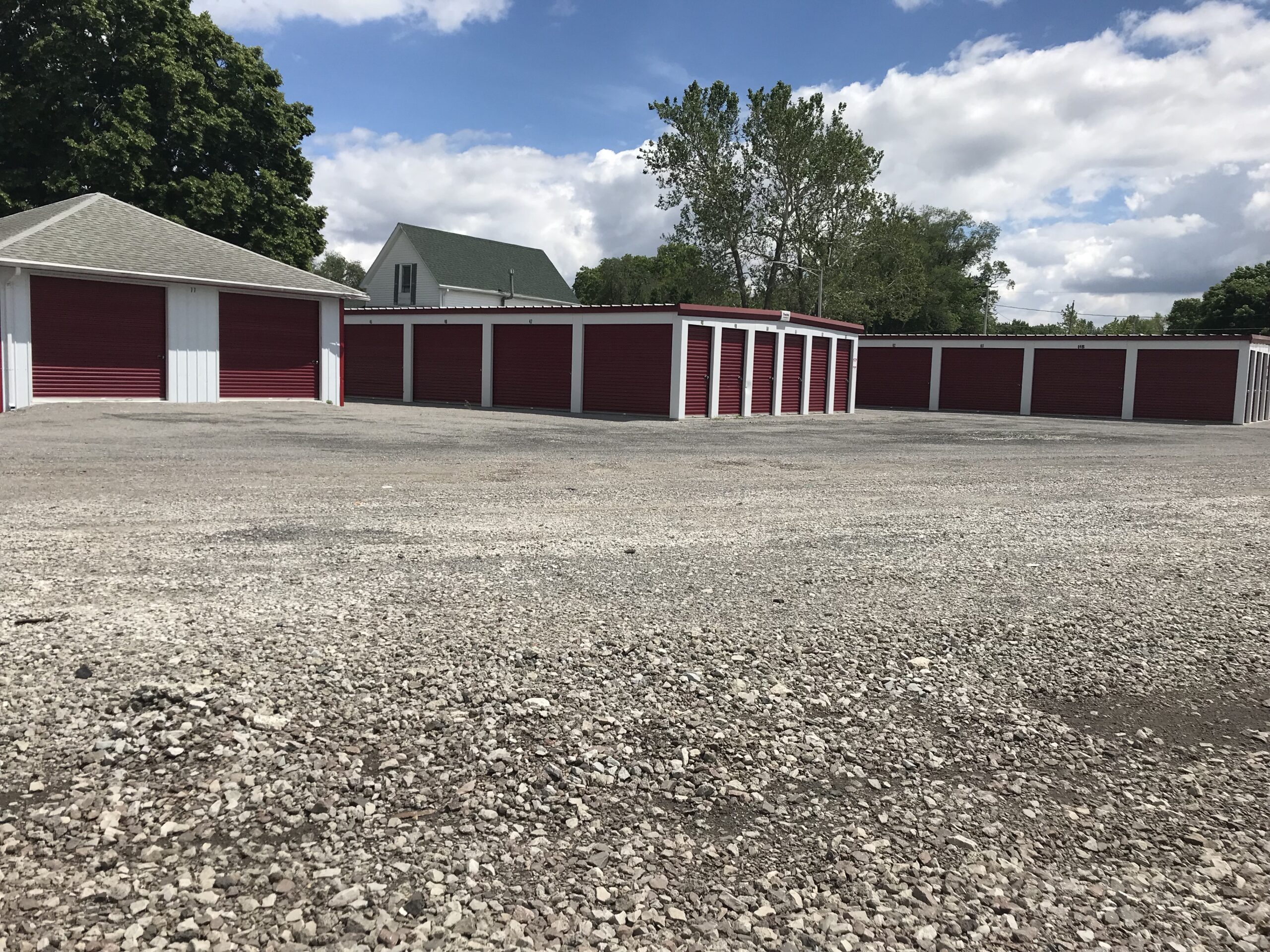 Storage buildings with red roll-up doors on a gravel lot